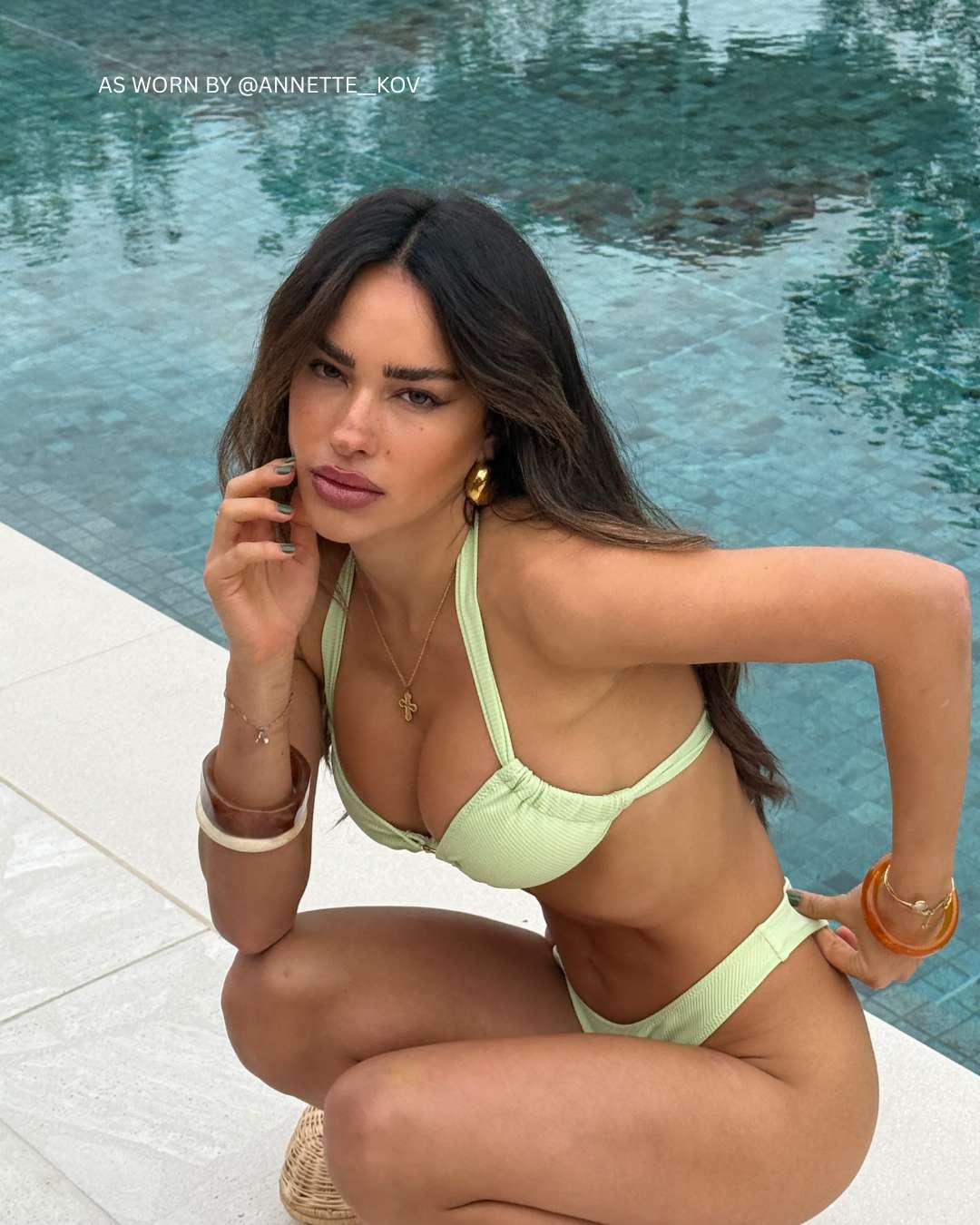 @annette_kov poolside in Lolé Swim’s green halter bikini with textured fabric and metallic gold ring accents.